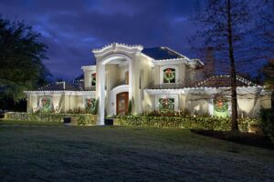 The Perfect Light Christmas light installation with roofline lights, window wreaths, and lit hedges on a Texas stucco estate