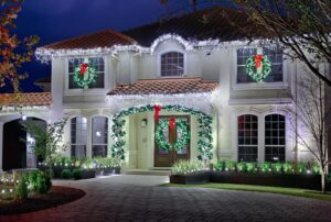 The Perfect Light Christmas light installation with icicle roofline lights, window wreaths, and door garland on a Texas stucco home