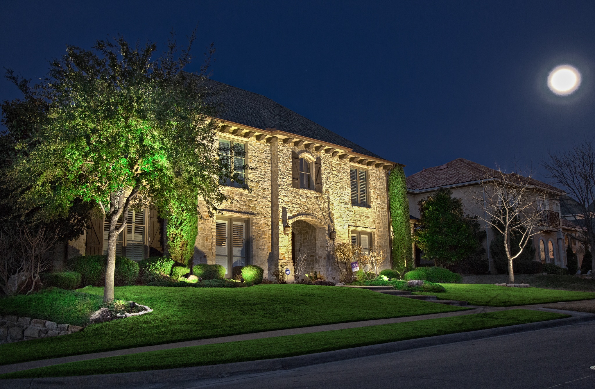 stone home with outdoor lighting