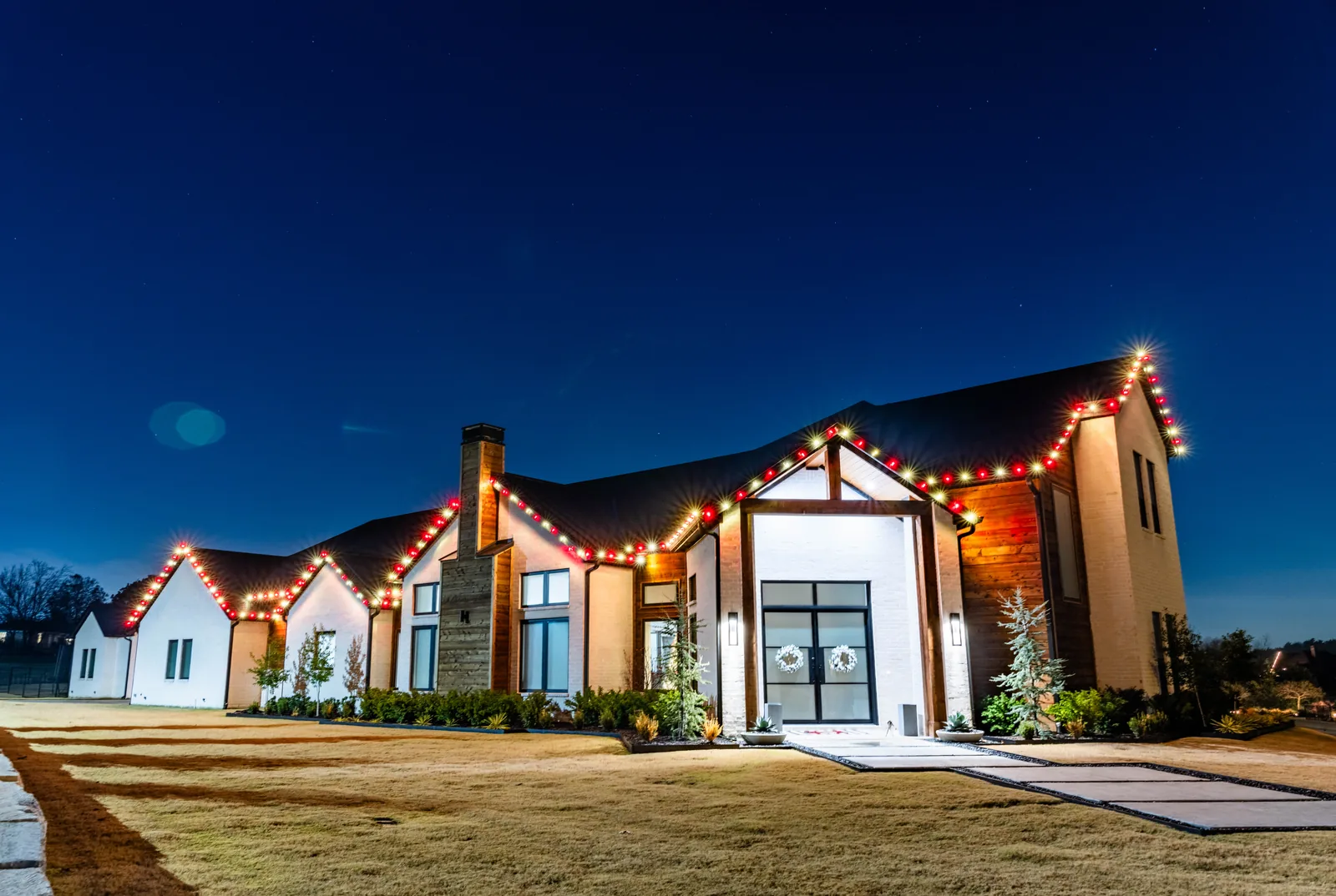 Modern home with roofline outlined in red and warm white Christmas lights, a $2,000 installation by The Perfect Light