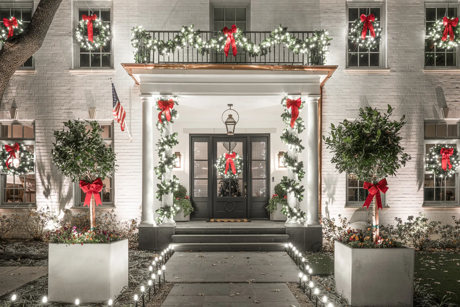 Professional Christmas lighting installation with matching garland, wreaths and ribbon accents on a home's entrance.