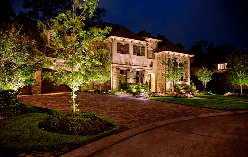 brown stone home with exterior landscape and lighting