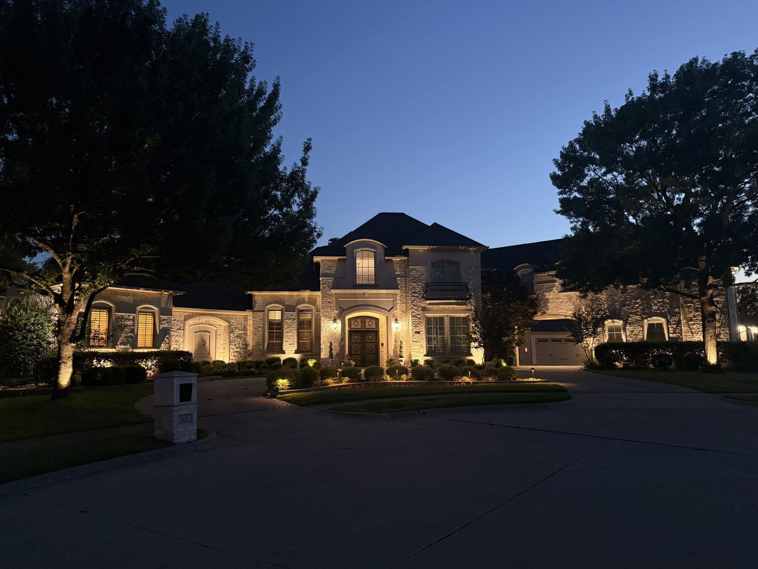 The Perfect Light landscape lighting installation on a Texas estate home, with facade uplighting, driveway and bed lighting at dusk.