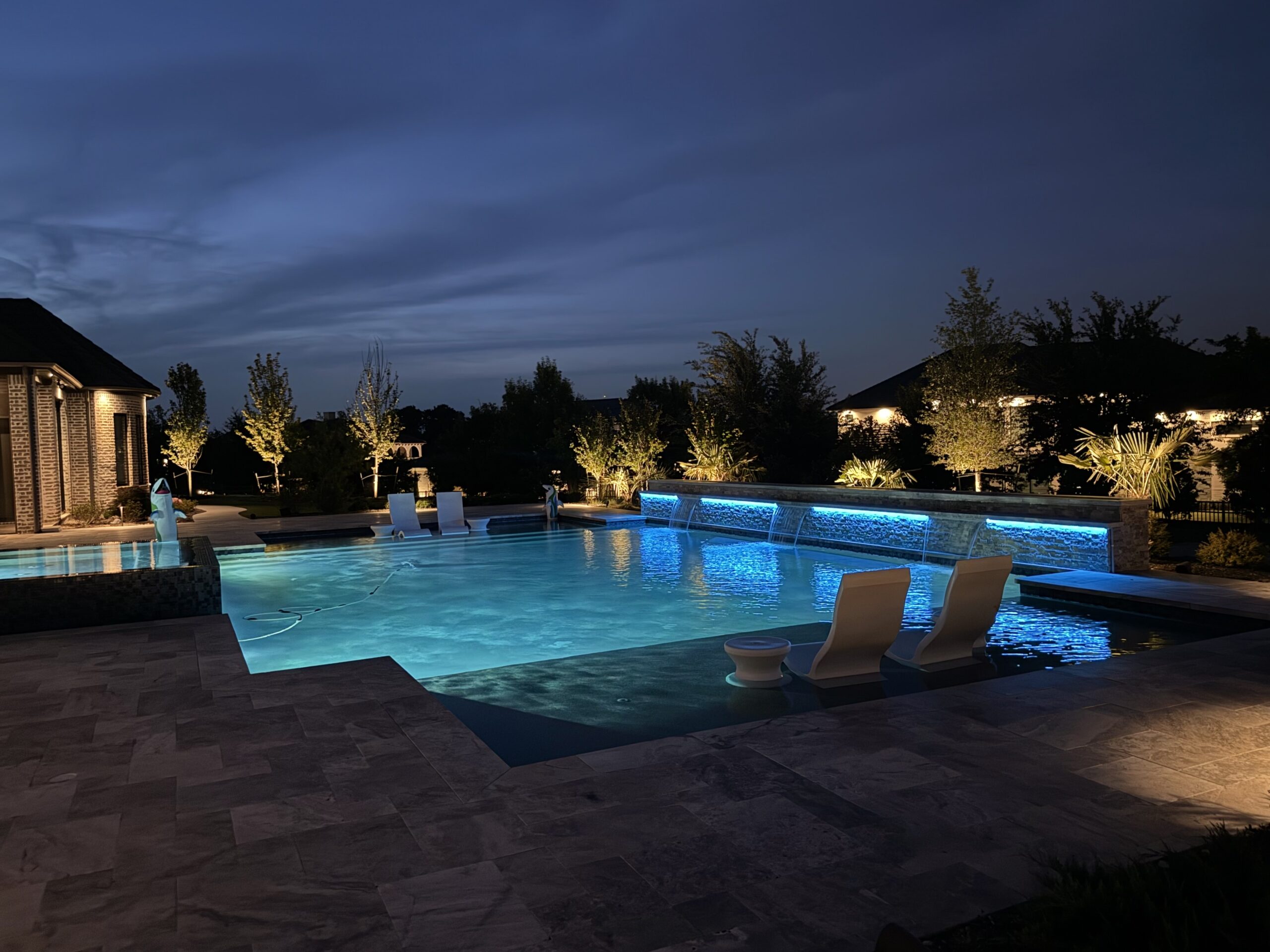 The Perfect Light landscape lighting illuminating a pool and outdoor living space at night in Texas